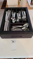 Overview of flatware in black storage box with knives, forks, spoons, and teaspoons visible.