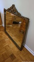Full angled view of the vintage ornate framed mirror showing the entire frame and mirror surface.