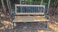 Front view of full bench showing wood slatted seat and back with wrought iron frame