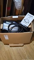 Top down view of Euroflex Monster SC60 steam cleaner in original box with hose, power cord, and some packaging plastic.