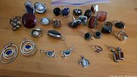Wide shot showing all rings, earrings, and pendants including rings with red jasper, amethyst, black onyx, and mother of pearl stones plus double hoop lapis earrings and bead cluster rings.