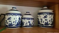 Group of three blue and white stoneware canisters on shelf