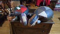 Two large leather stuffed turtles side by side on a wooden chest, showing patchwork colored leather shells and gray legs.