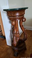 Front view of plant stand showing carved wood legs and green marble top