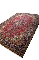 Angled overview of rug showing red central field and navy border