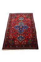 Rectangular handmade Persian Tabriz-style rug with central floral medallion, red field, blue, green and white accents, black patterned border.