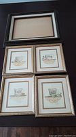 Five frames displayed on dark surface: four containing signed art prints of teacups by Sandy Clough and one empty frame