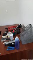 Full view of desk with stapler, tape dispenser, pens, file holders and calculator visible