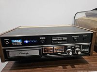 Front view of Akai CR-81D showing brand label, track indicator, cartridge slot, VU meters, control buttons, and volume knobs.