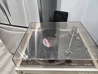 Vintage DUAL 506 belt drive turntable with transparent dust cover on, playing record.