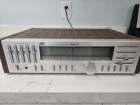 Front and top angled view of JVC R-S33 stereo receiver showing graphic equalizer sliders, tuning dial, and control knobs.