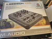 Box of M-Audio X-Session Pro USB MIDI DJ Mixer Controller showing product image and specifications.