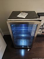 Front view of mini beverage refrigerator with glass door illuminated by interior LED lighting