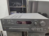 Front angle view of NAD C 720BEE stereo receiver showing buttons, volume knob, and display screen.