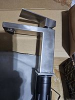 Faucet standing upright, showing square modern design and brushed stainless steel finish.
