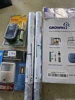 Overview showing Kodak solar charger with battery, two rolls of window film, Growns bottle warmer box, and motion sensor light packaging.