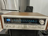 Front view showing wood veneer top and aluminum front panel with tuner display and control knobs