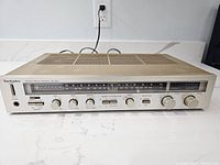 Front view of Technics SA-203 stereo receiver showing model markings, tuning scale, and control knobs.