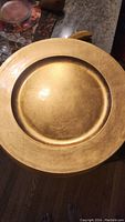 Top view of a single gold decorative plate showing the metallic finish and textured surface.