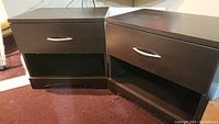 Two brown wooden drawers each with one drawer and an open shelf beneath, placed on carpeted floor showing surface wear.