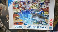 Puzzle box front showing underwater ocean scene with sharks, fish, coral reefs, and aquatic life. Box indicates 3000 pieces and Ravensburger brand.
