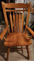 Photo of one hardwood chair showing traditional spindle back design, armrests, turned legs, and contoured seat.