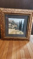 Full image of the framed Italian landscape painting showing the entire piece with the gold frame and wooden floor background.