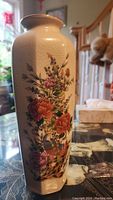 Photo of a tall ceramic Japanese vase with intricate painted flowers and birds on a light beige crackled glaze background.