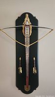 Full view of the mounted King Arthur style crossbow with decorative bolts and plaque.