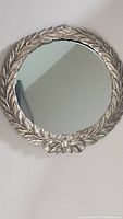 Photo of a 15 inch round wall mirror with detailed olive branch styled frame and clear mirror surface.
