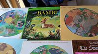 Photo showing colorful vinyl album covers including Disney's Bambi, Lady and the Tramp, and others with animal and Disney-themed artwork.