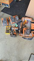 Rigid cordless drill, 18V batteries, and chargers in garage setting.