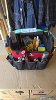 Front view of red and black Husky tool tote filled with assorted hand tools, showing tool handles and pockets.