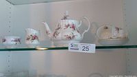 Shelf display showing full tea set: teapot, creamer, sugar bowl, two teacups with saucers
