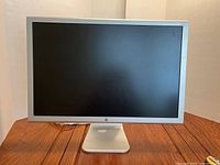 Front view of the Apple iMac 23 inch Cinema HD monitor showing screen and aluminum stand on wood surface.