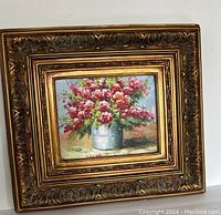 Full view of the framed painting showing the floral bouquet and ornate frame.