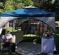 Erected 10'x10' canopy in outdoor market setting with tables and chair inside