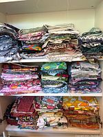 Folding cabinet shelves filled with stacks of assorted cotton fabric remnants in various prints and colors