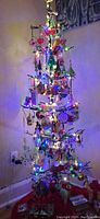 Fully decorated metal display tree with multicolored lights and various Christmas ornaments as a usage example, not included.