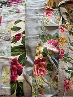 Six pieces of vintage bark cloth fabric, some with large floral patterns and some lighter solid pastel fabrics, showing texture and minor wear.