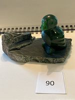 Photo of jade puffin sculpture showing polished bird on rough stone base from side angle.