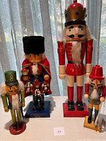 Four wooden nutcrackers displayed with varying heights and colorful uniforms under natural light.