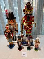 Six wooden figurines arranged on a table with a curtain background, showing full lot from front