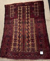 Full view of the rectangular wool rug showing geometric patterned design in rich reds and beiges with slight misshaping.
