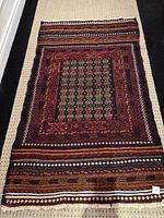 Full view of vintage wool rug showing embroidered design and size relative to floor; rug is rectangular and flat woven.