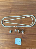 Two Italian sterling silver necklaces with four unique sterling silver charms displayed together on wood background