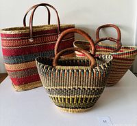 Front view of all five straw bags showing size and color variety: three large vintage bags and two smaller contemporary bags