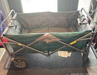 Front view of the collapsible wagon showing green canvas body and metal frame structure.