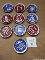Photo of 11 Rosenthal monthly coasters arranged on a surface showing alternating red and blue designs with white illustrations representing months.