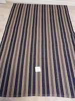 Top view of blue and beige striped rug laid flat on carpeted floor.